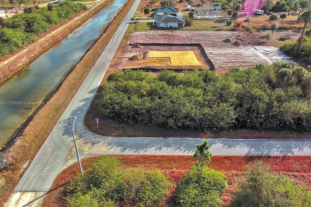 An aerial view shows a cleared residential lot with a canal alongside a paved road — 4506 E 19TH STREET, LEHIGH ACRES, FL