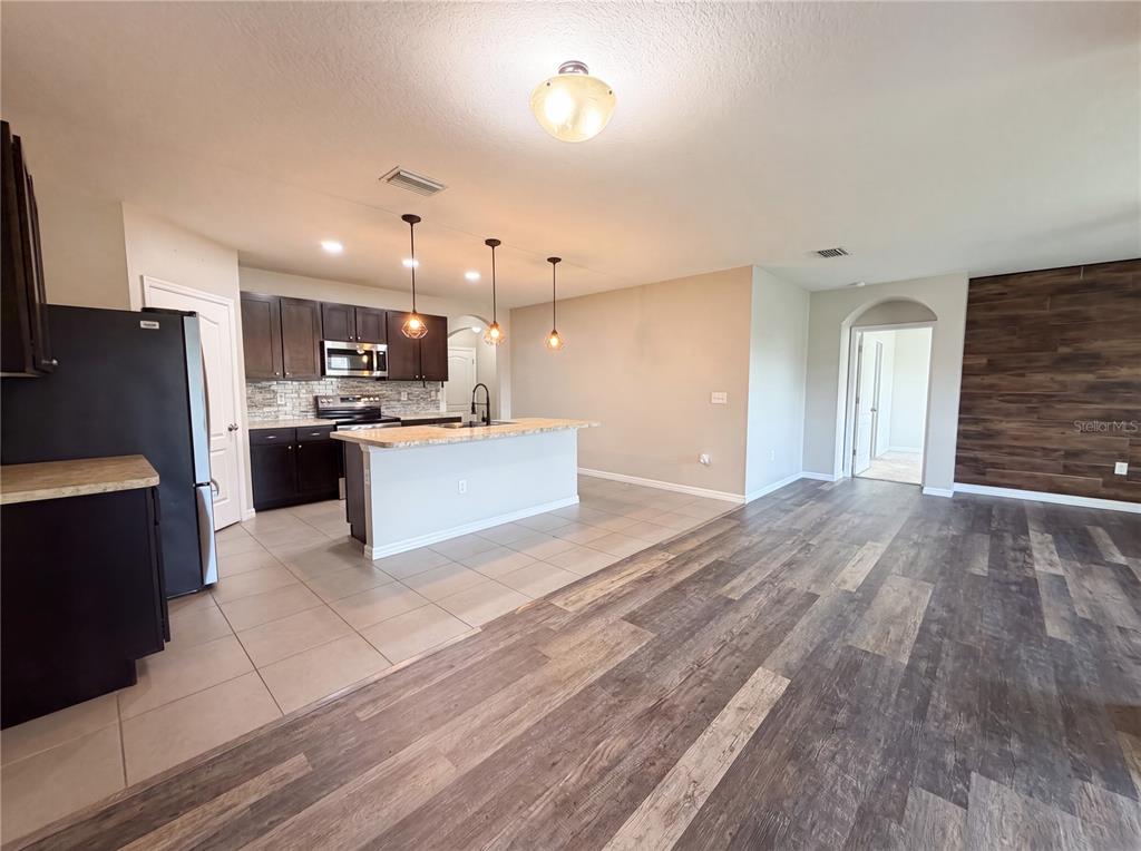 An open-concept kitchen with dark cabinets and a breakfast bar overlooks a living area — 16415 TREASURE POINT DRIVE, WIMAUMA, FL