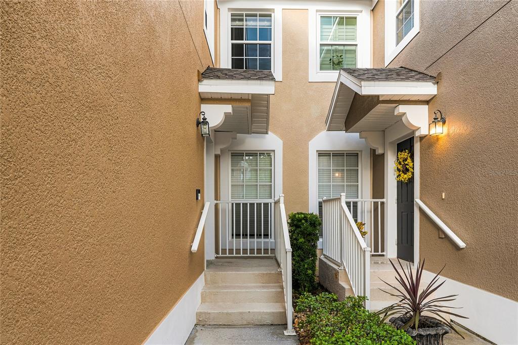 Two adjacent townhome entrances feature stucco walls, concrete steps, and small covered porches — 417 HILGARD COVE UNIT ., SANFORD, FL