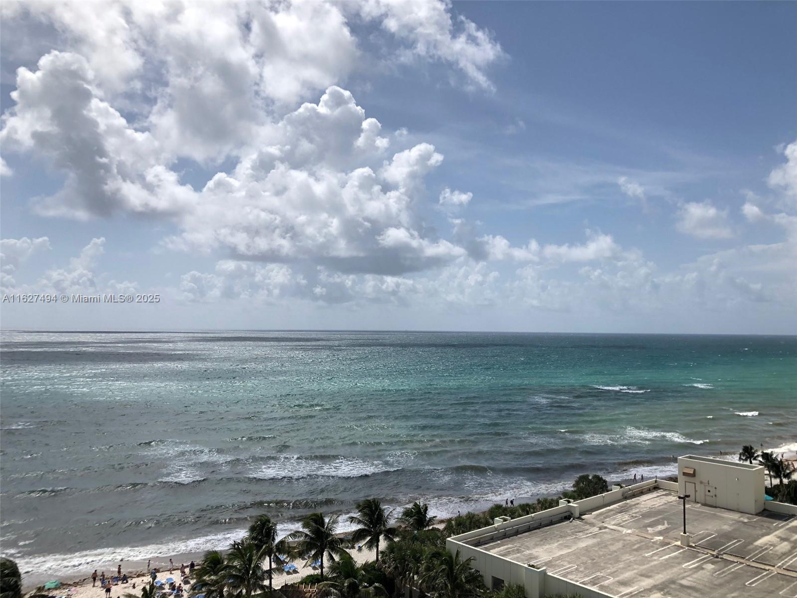 An elevated view of a beach, ocean, and a parking structure under a cloudy sky — 3801 OCEAN DR # 10H, Hollywood FL 33019, HOLLYWOOD, FL