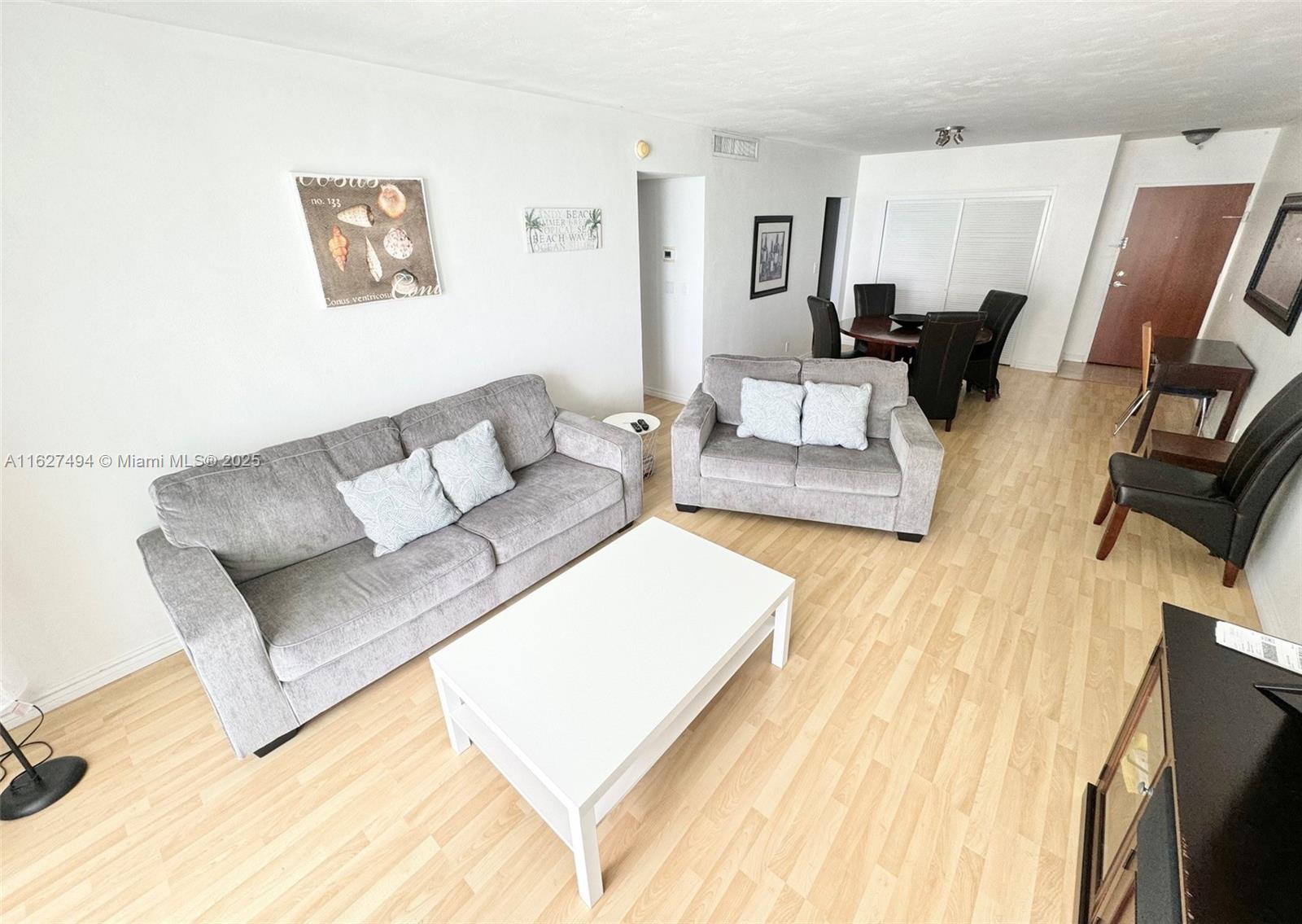 A living room features gray sofas, a white coffee table, and light wood flooring — 3801 OCEAN DR # 10H, Hollywood FL 33019, HOLLYWOOD, FL