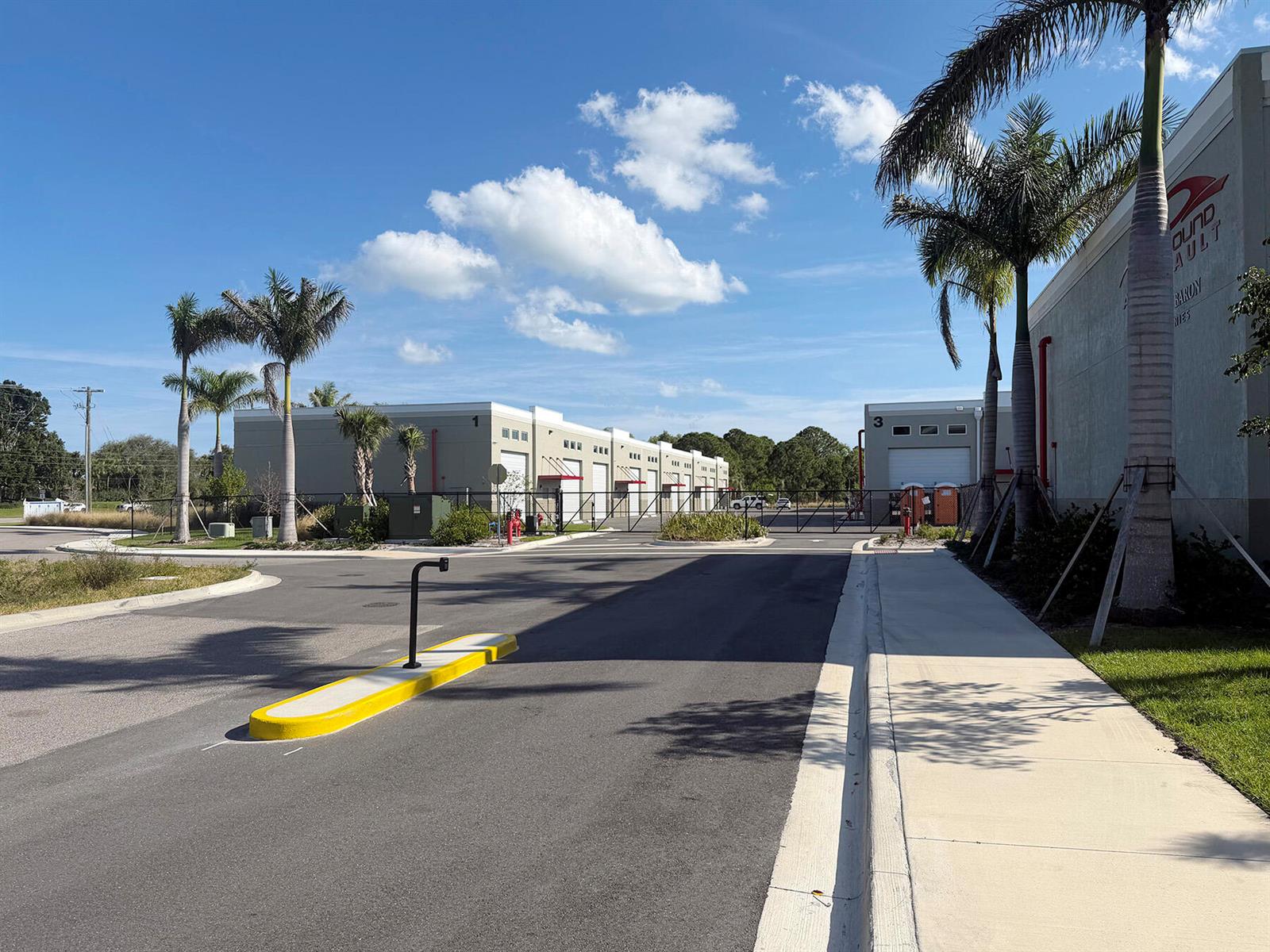 An exterior view of a commercial warehouse complex with palm trees and a paved driveway — 7040 SE Federal Highway # 63, Stuart FL 34997, STUART, FL