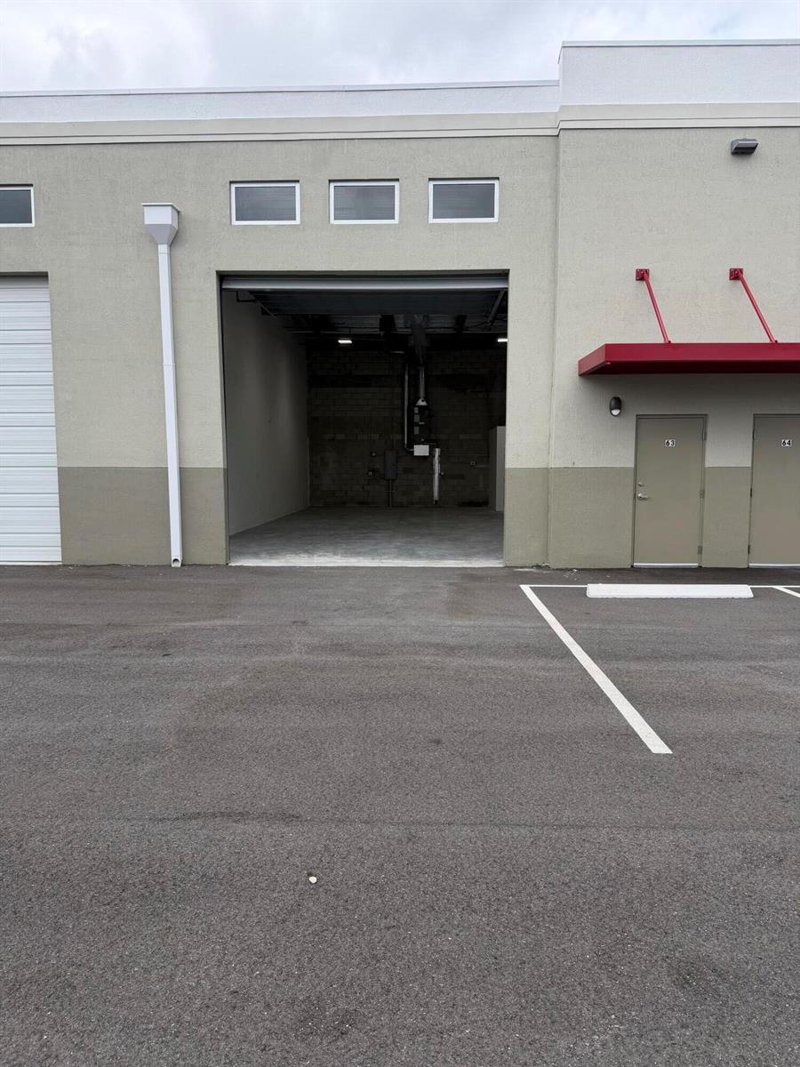 An exterior view of a commercial warehouse unit with an open bay door and adjacent doors — 7040 SE Federal Highway # 63, Stuart FL 34997, STUART, FL