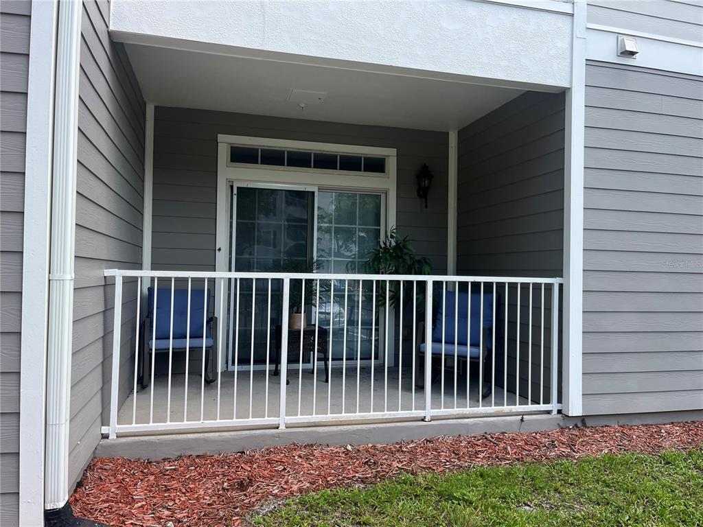 A ground-level patio features a white metal railing, two blue chairs, and sliding glass doors — 3177 FELTRIM PLACE UNIT 101, KISSIMMEE, FL