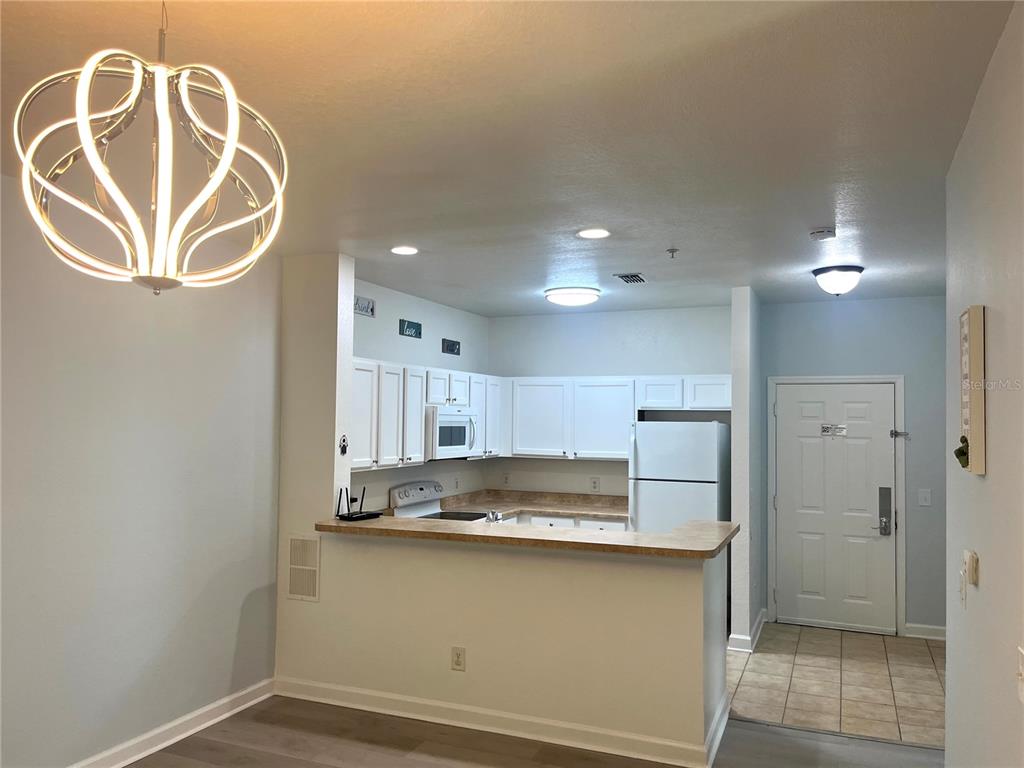 A kitchen with white cabinets and a breakfast bar opens to a dining area — 3177 FELTRIM PLACE UNIT 101, KISSIMMEE, FL