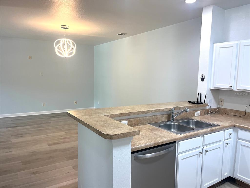 A kitchen with white cabinets and a breakfast bar overlooks an open living area — 3177 FELTRIM PLACE UNIT 101, KISSIMMEE, FL
