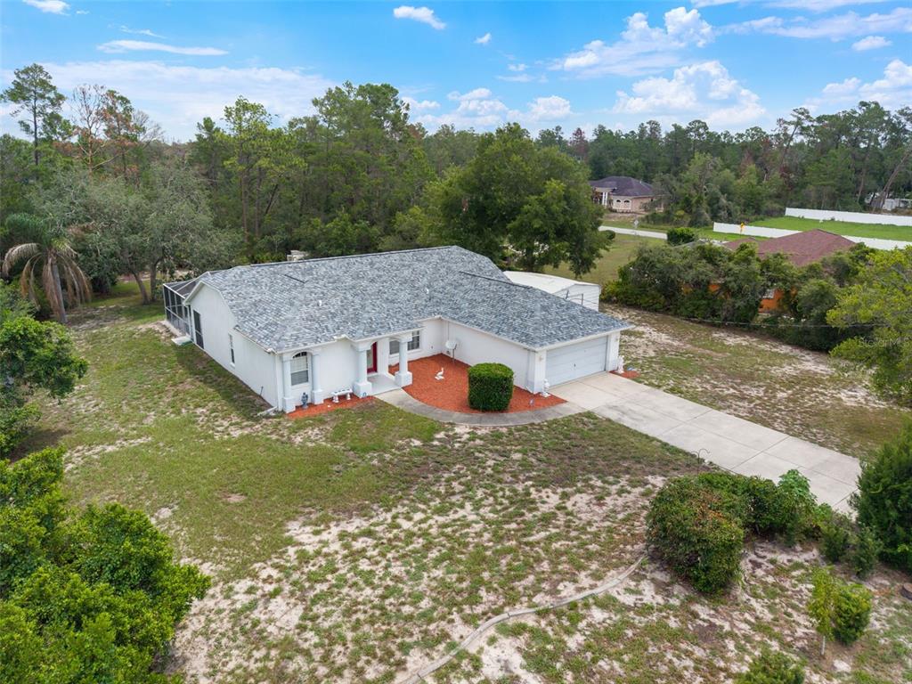 An aerial view shows a white single-story house with a gray roof and a driveway — 7401 BLACKBIRD AVENUE, WEEKI WACHEE, FL
