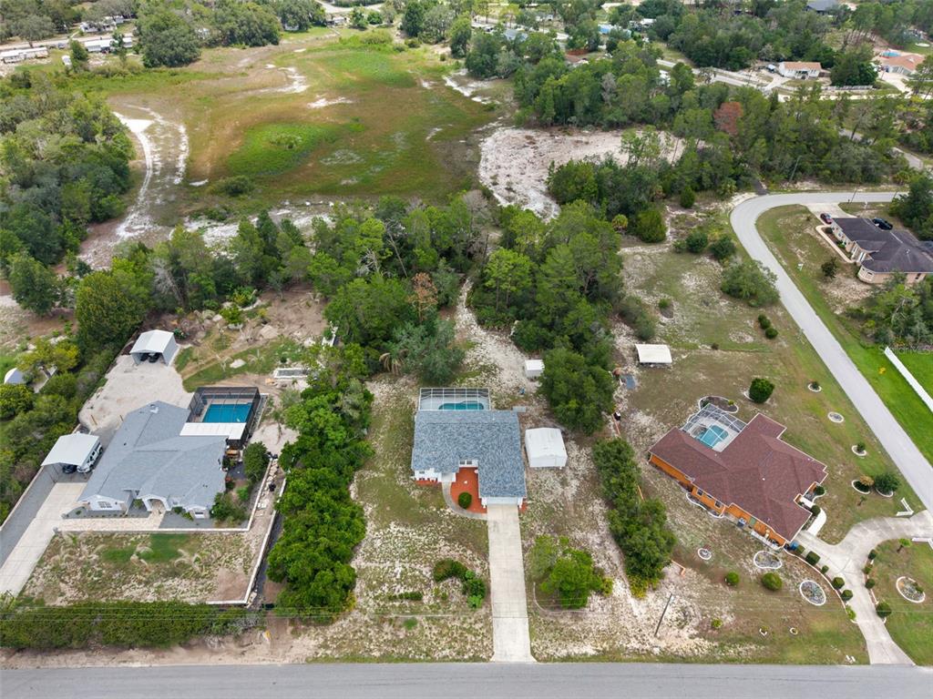 An aerial view shows three houses with swimming pools situated on large, wooded residential lots — 7401 BLACKBIRD AVENUE, WEEKI WACHEE, FL