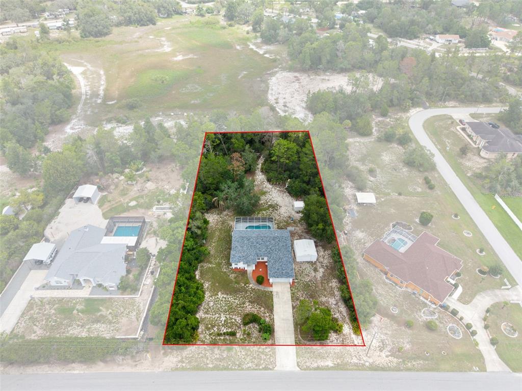 An aerial view shows a house with a pool on a large, partially wooded lot — 7401 BLACKBIRD AVENUE, WEEKI WACHEE, FL