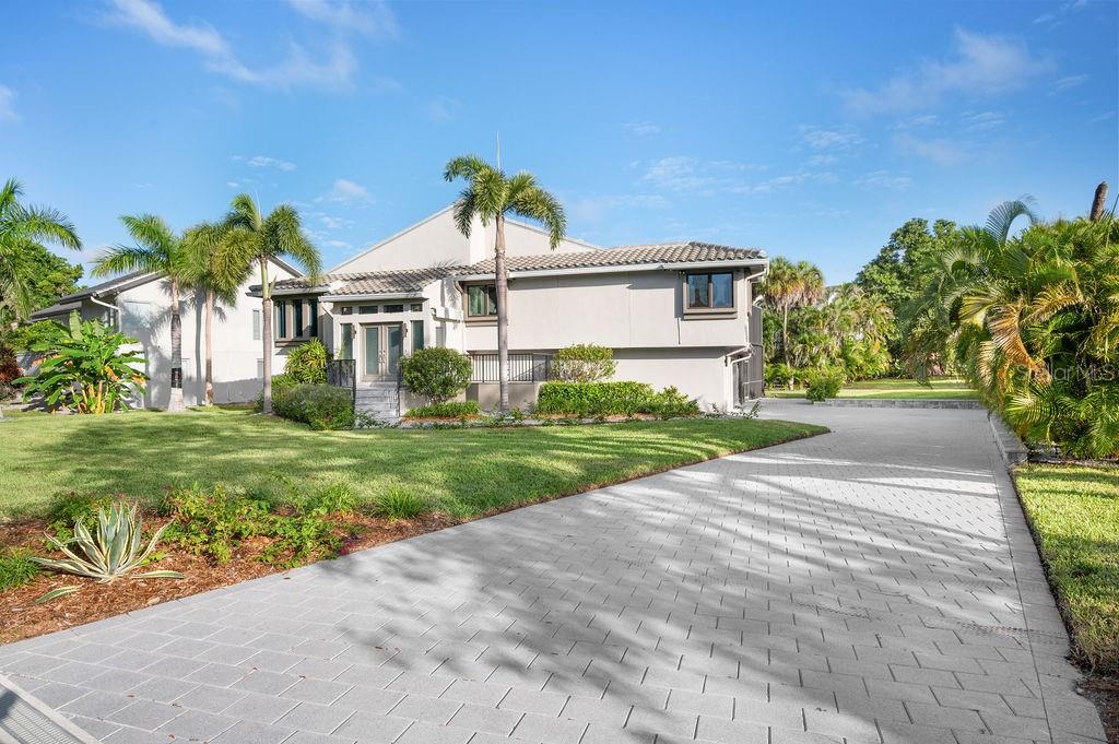 A two-story house with a paved driveway, palm trees, and a green lawn — 3210 BAYOU SOUND, LONGBOAT KEY, FL