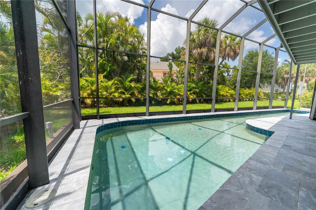 A screened-in patio features a swimming pool with blue tile trim and stone decking — 3210 BAYOU SOUND, LONGBOAT KEY, FL