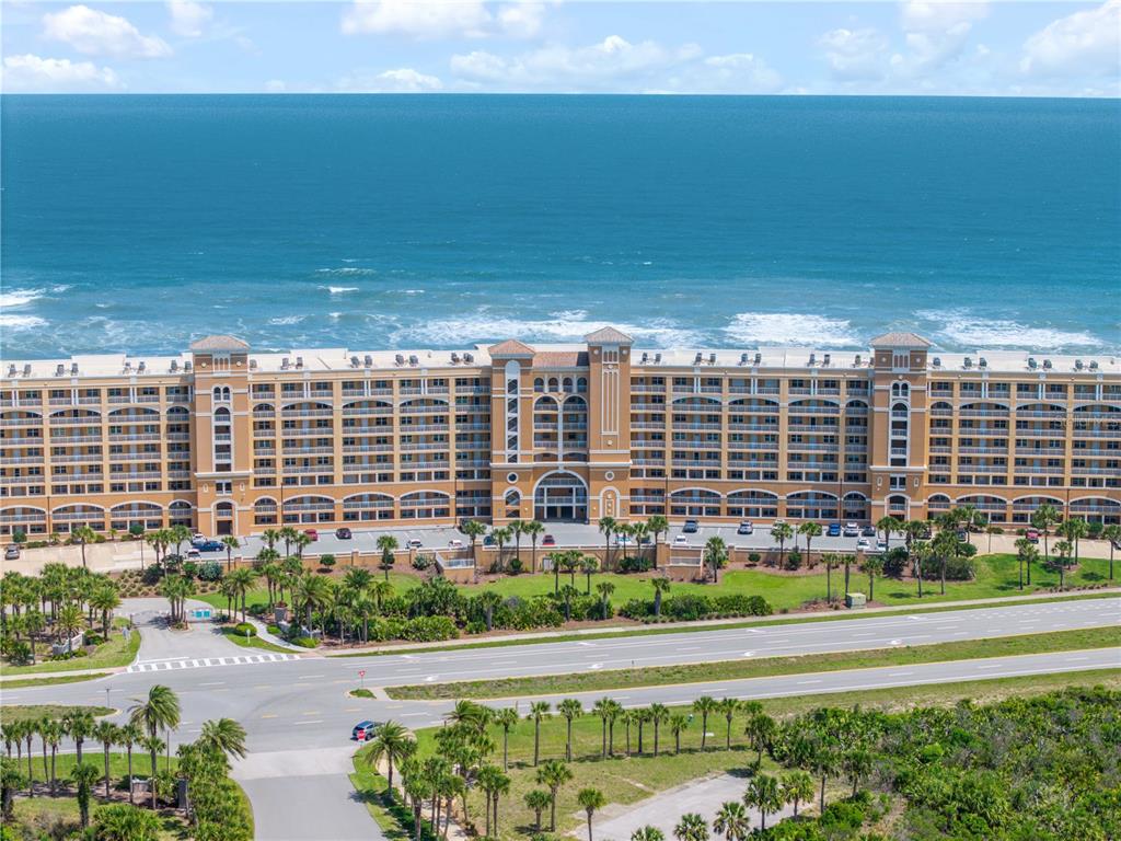 An aerial view shows a large, multi-story tan resort building situated along the oceanfront — 60 SURFVIEW DRIVE UNIT 510, PALM COAST, FL