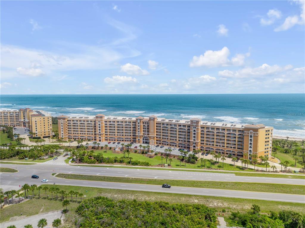 An aerial view shows a large, multi-story tan resort building situated along a sandy beach — 60 SURFVIEW DRIVE UNIT 510, PALM COAST, FL