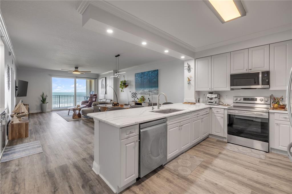 A modern kitchen with white cabinets and marble countertops overlooks an open living area — 60 SURFVIEW DRIVE UNIT 510, PALM COAST, FL