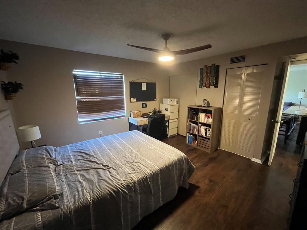 A bedroom features a bed, a desk, a bookshelf, and a closet with louvered doors — 2632 HIDDEN LAKE DR N UNIT B, SARASOTA, FL