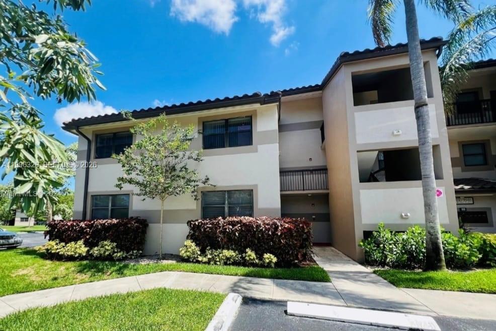 A two-story apartment building with beige stucco walls, dark trim, and landscaped bushes — 9885 Nob Hill Ct # 9885, Sunrise FL 33351, SUNRISE, FL