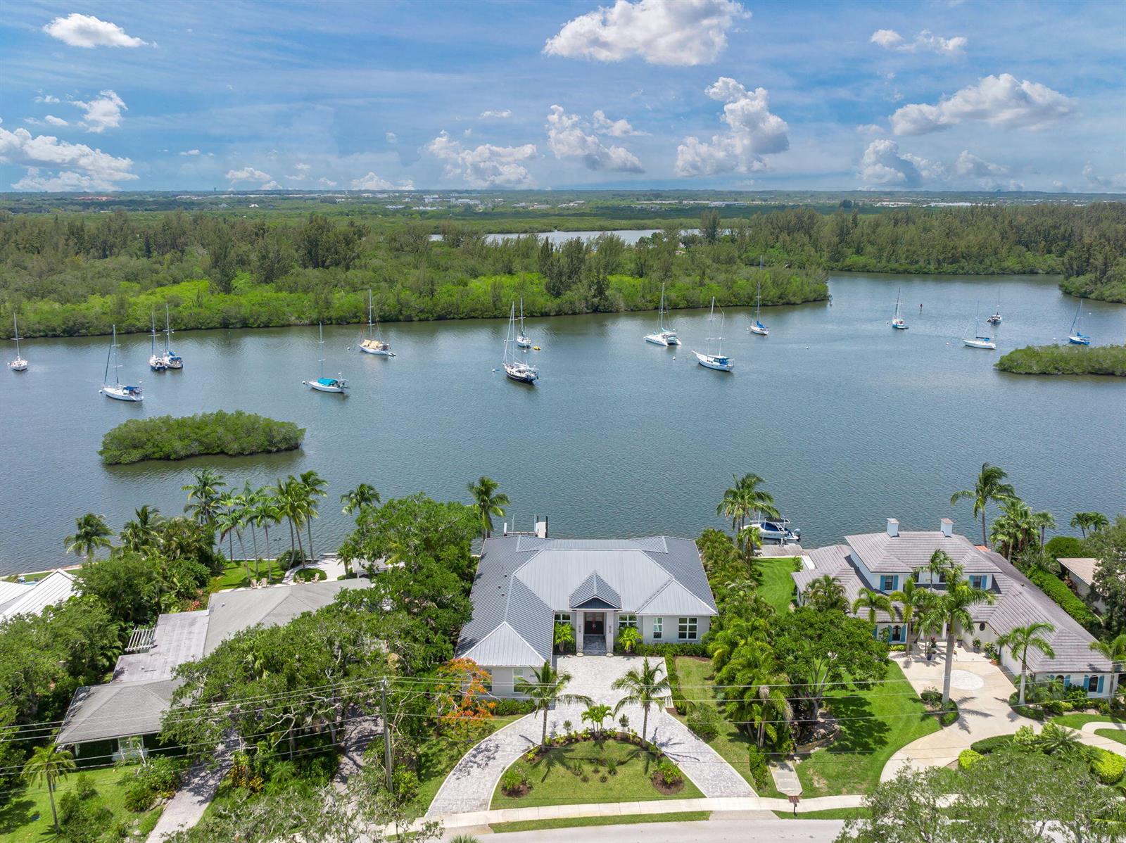 An aerial view shows a waterfront house with a metal roof and a circular driveway — 3937 Indian River Drive E, Vero Beach FL 32963, VERO BEACH, FL