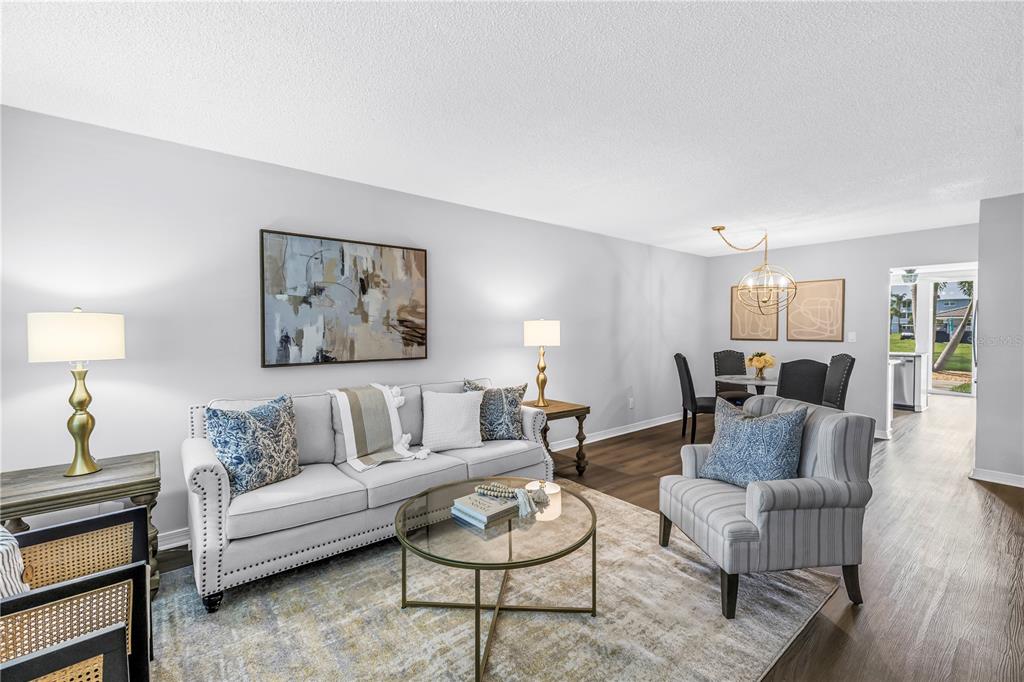 A living room features a grey sofa, a glass coffee table, and an adjacent dining area — 4715 BAY STREET NE UNIT 135, ST PETERSBURG, FL