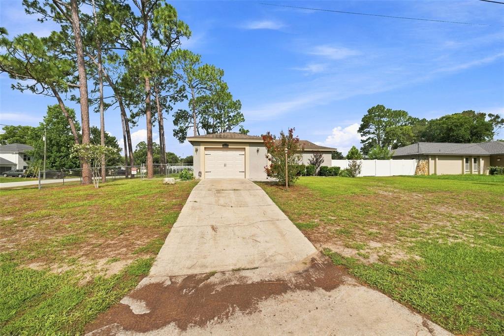 A single-story house with a concrete driveway and a one-car garage sits on a lawn — 2077 ARBUCKLE ROAD, SPRING HILL, FL