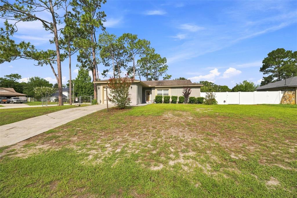 A single-story house with a concrete driveway, a front lawn, and a white privacy fence — 2077 ARBUCKLE ROAD, SPRING HILL, FL