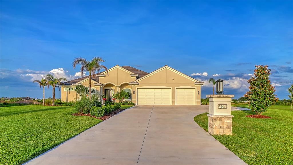 A single-story house with a beige stucco exterior and a three-car garage — 3554 RECURVE CIRCLE, SARASOTA, FL