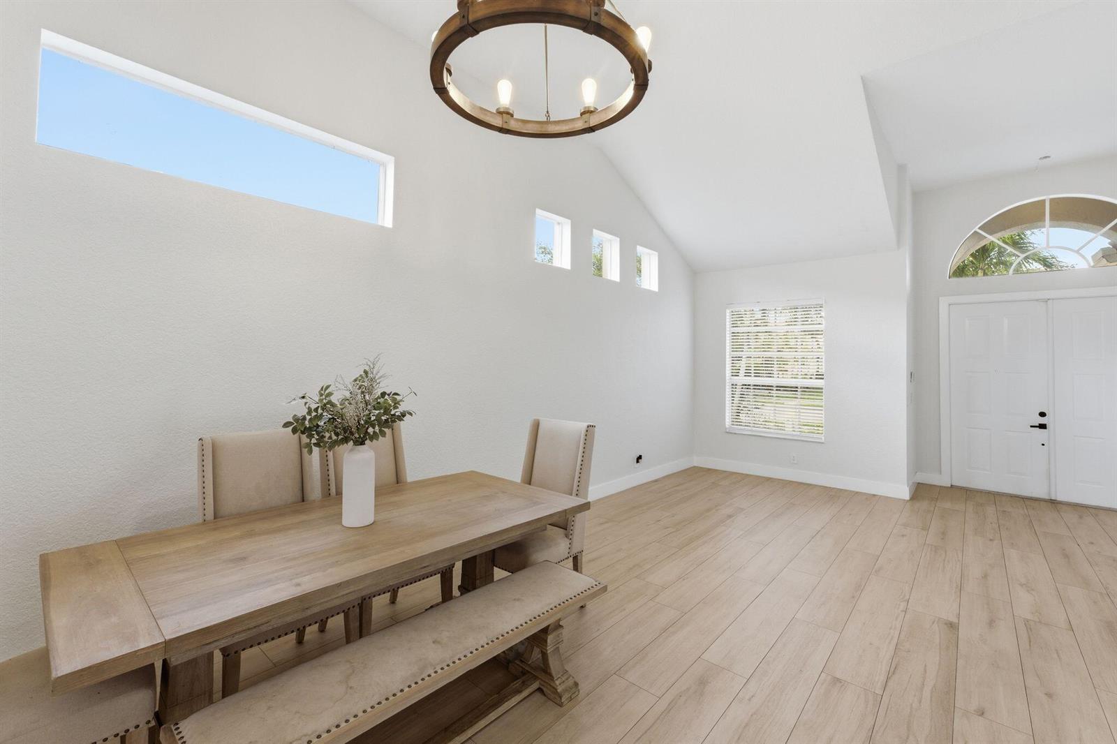 A dining area features a wooden table, a bench, chairs, and a vaulted ceiling — 12339 NW 77th Manor, Parkland FL 33076, PARKLAND, FL