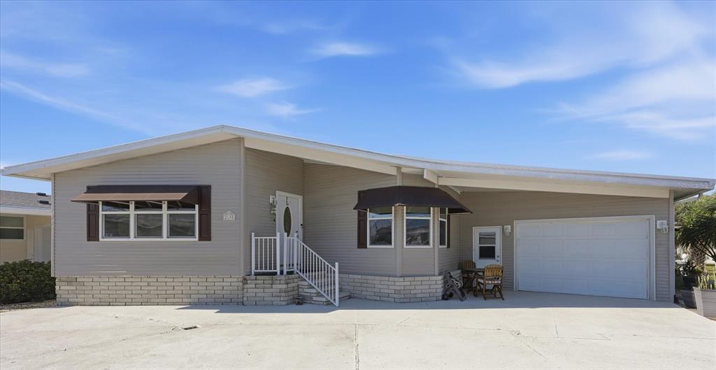 A single-story house with light gray siding, a white garage door, and a concrete driveway — 2108 ILLINOIS AVENUE, BRADENTON, FL