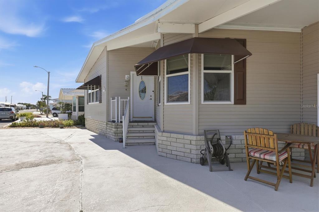 A beige mobile home features a concrete patio, a small staircase, and brown window awnings — 2108 ILLINOIS AVENUE, BRADENTON, FL