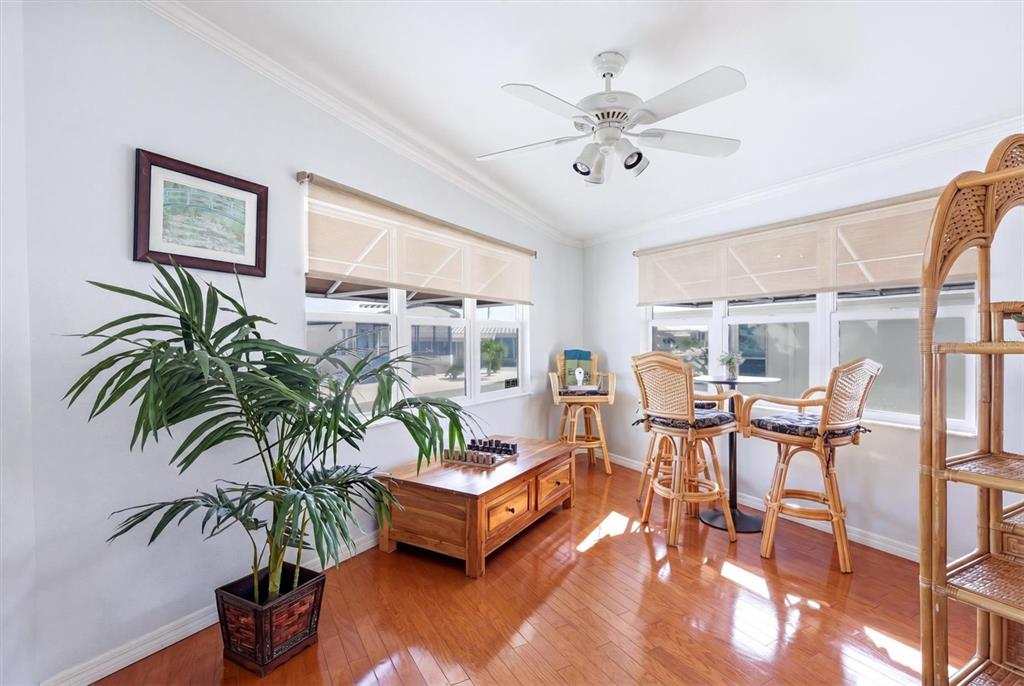 A sunroom features hardwood floors, a ceiling fan, a wooden coffee table, and wicker chairs — 2108 ILLINOIS AVENUE, BRADENTON, FL