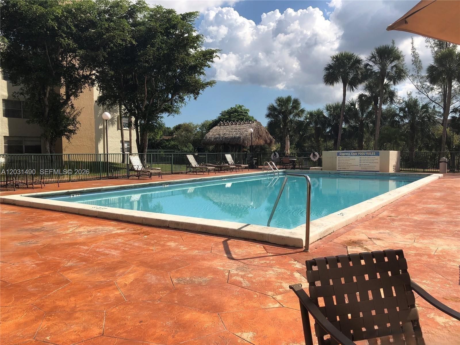 A rectangular swimming pool is surrounded by a stamped concrete deck and lounge chairs — 14250 SW 62nd St # 325, Miami FL 33183, MIAMI, FL