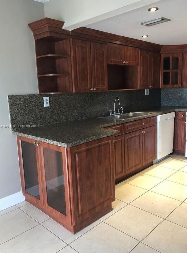 A kitchen features dark wood cabinets, granite countertops, and light-colored tile flooring — 14250 SW 62nd St # 325, Miami FL 33183, MIAMI, FL