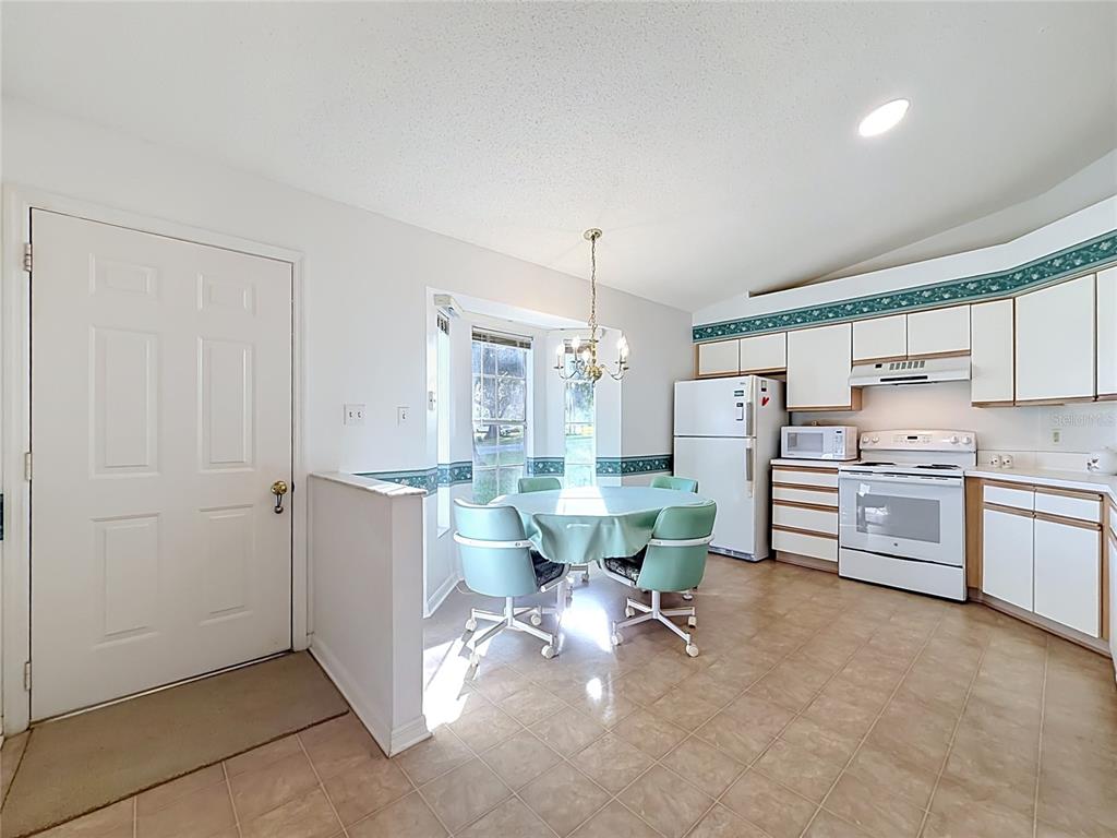 A kitchen with white cabinets, a dining area with a round table, and tile flooring — 25014 PINE HILL, LEESBURG, FL