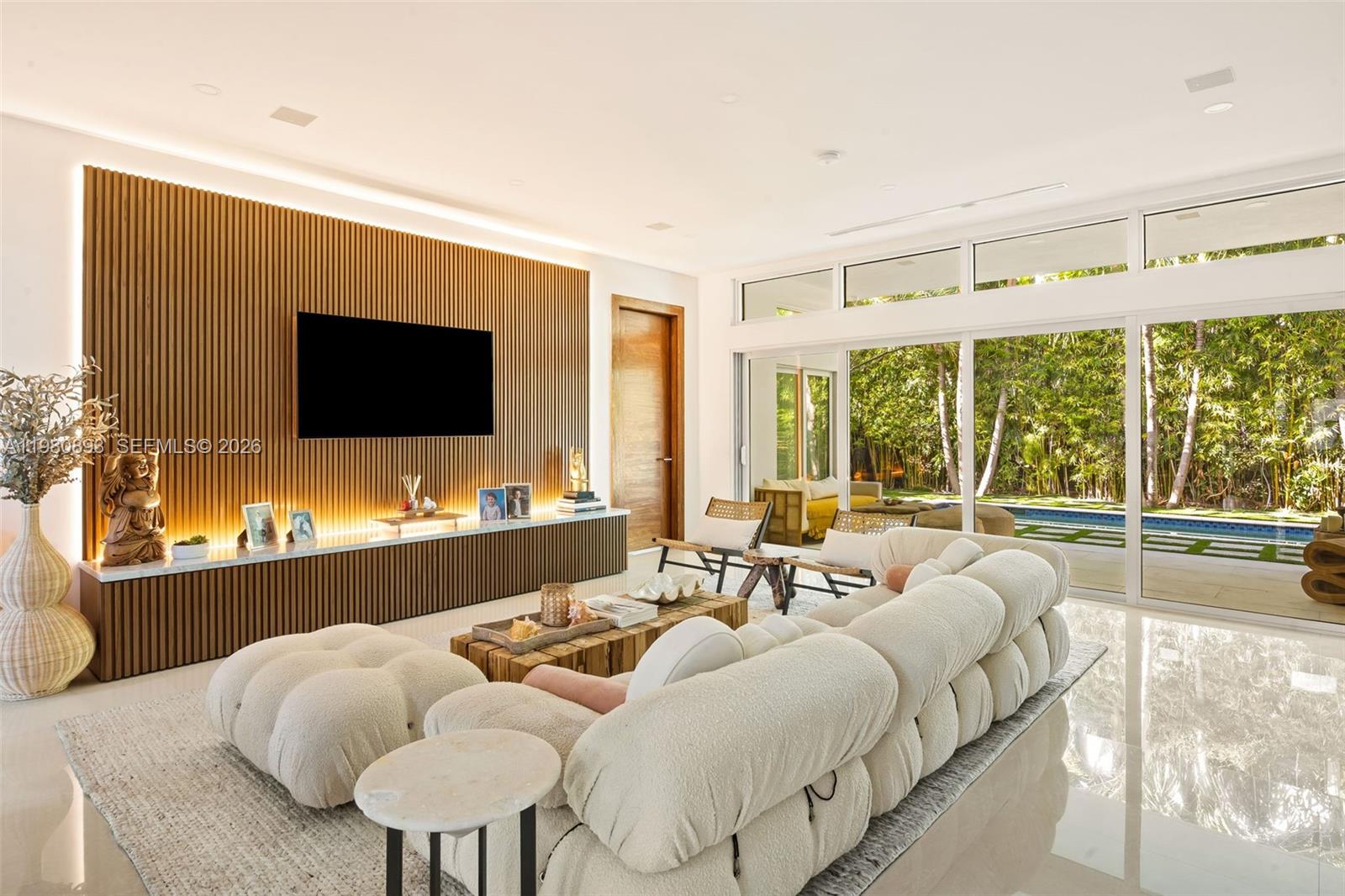 A modern living room features a slatted wood accent wall, white sofa, and floor-to-ceiling windows — 865 W 47th St, Miami Beach FL 33140, MIAMI BEACH, FL