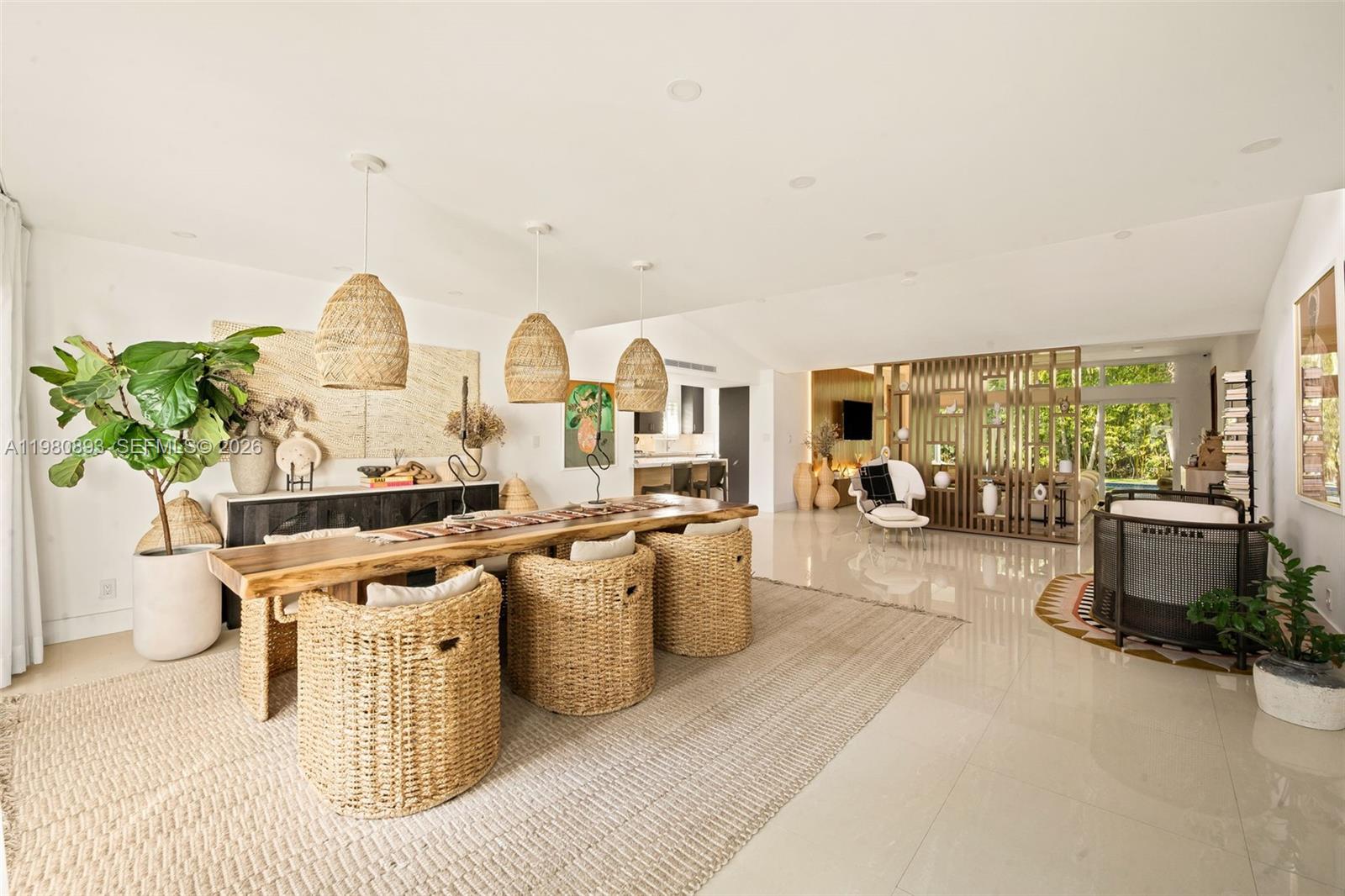A dining area with a live-edge table and woven chairs sits in an open-concept room — 865 W 47th St, Miami Beach FL 33140, MIAMI BEACH, FL
