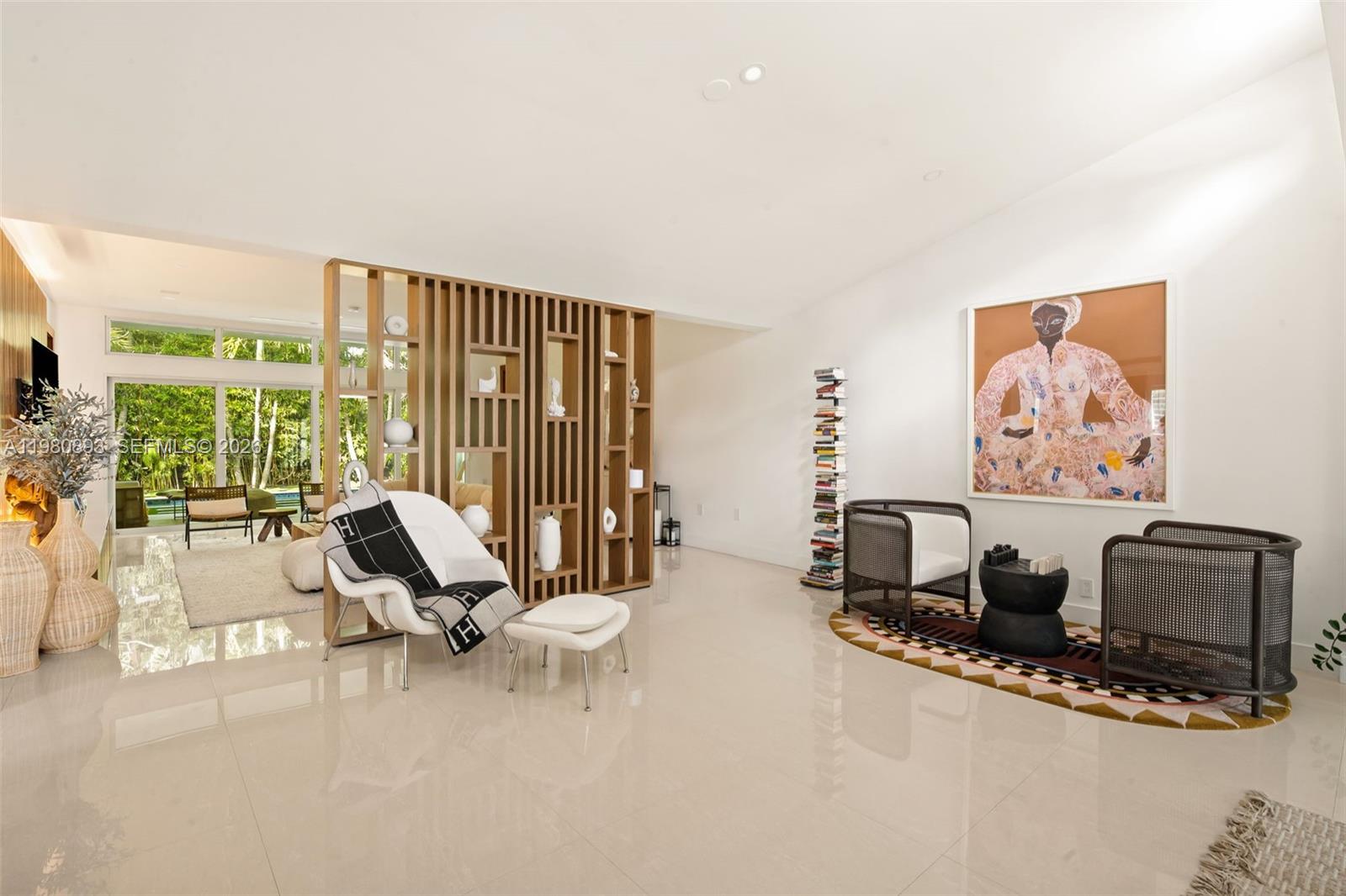 A bright living room features a wooden slat room divider, modern furniture, and large windows — 865 W 47th St, Miami Beach FL 33140, MIAMI BEACH, FL