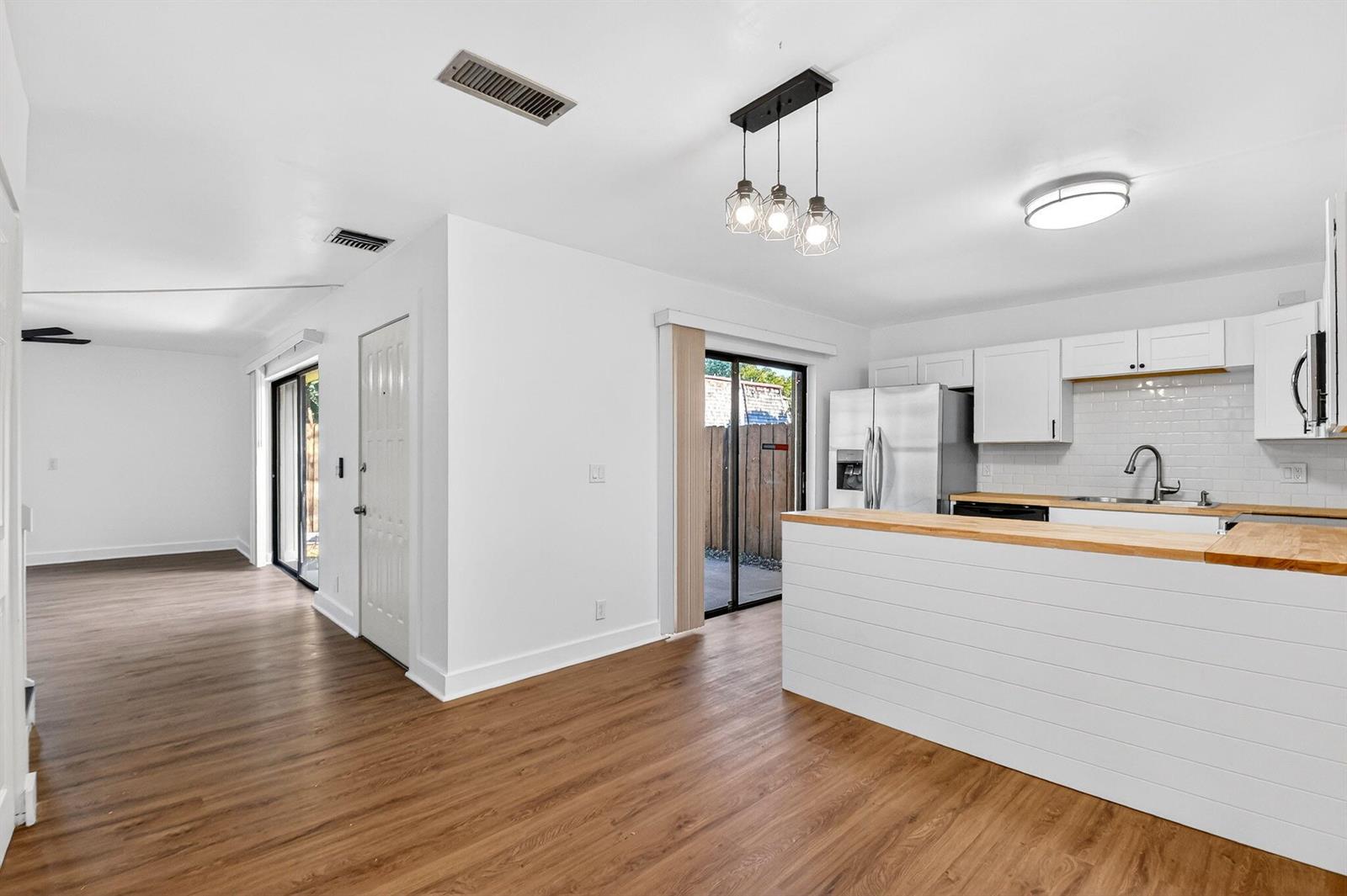 A kitchen with white cabinets and a wood countertop island opens to a living area — 198 Lake Arbor Drive, Palm Springs FL 33461, PALM SPRINGS, FL