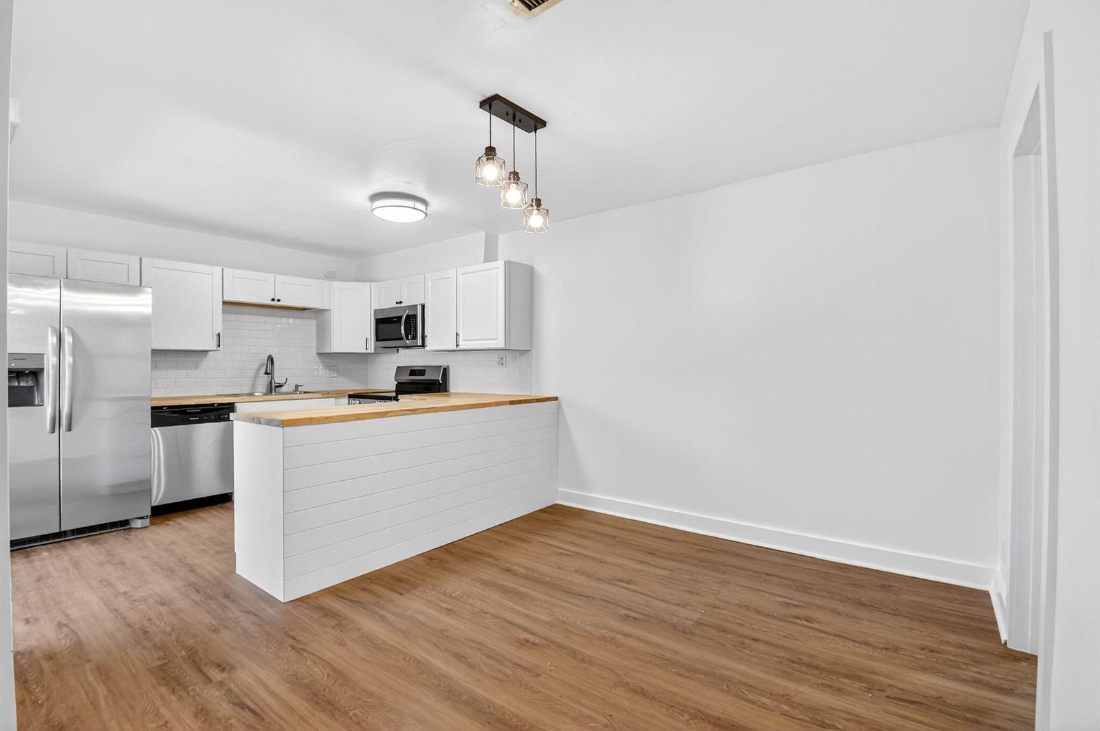 A kitchen features white cabinets, stainless steel appliances, a wood countertop, and wood-look flooring — 198 Lake Arbor Drive, Palm Springs FL 33461, PALM SPRINGS, FL