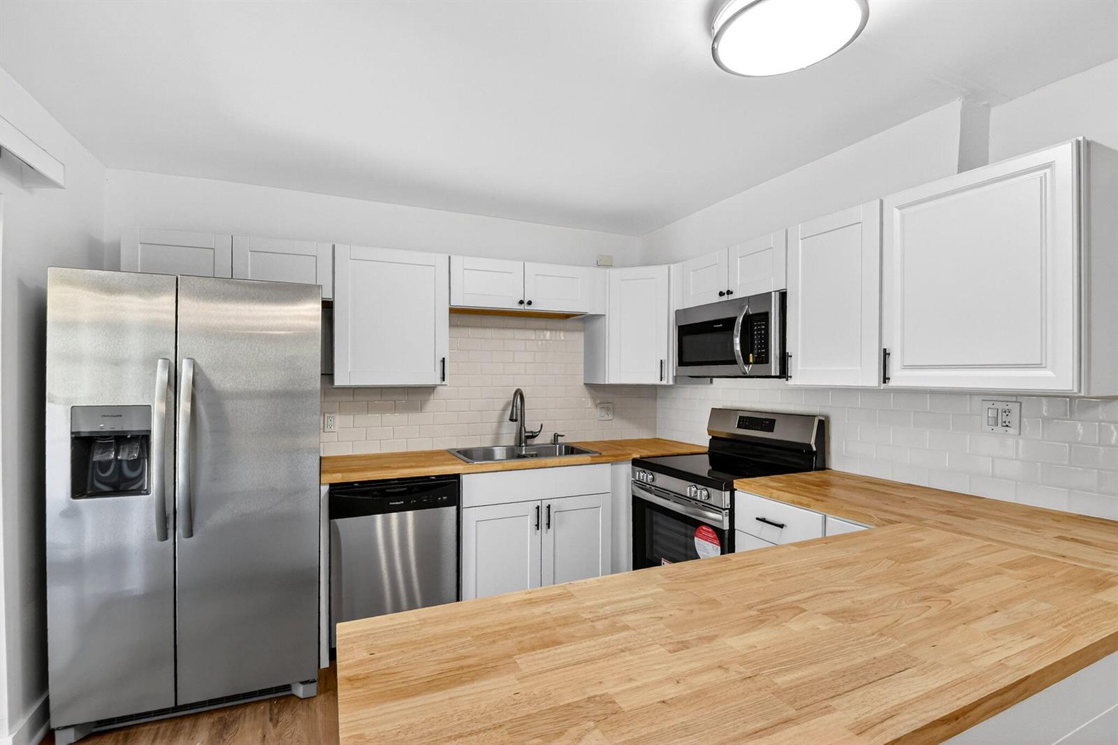 A kitchen with white cabinets, stainless steel appliances, and light wood countertops — 198 Lake Arbor Drive, Palm Springs FL 33461, PALM SPRINGS, FL