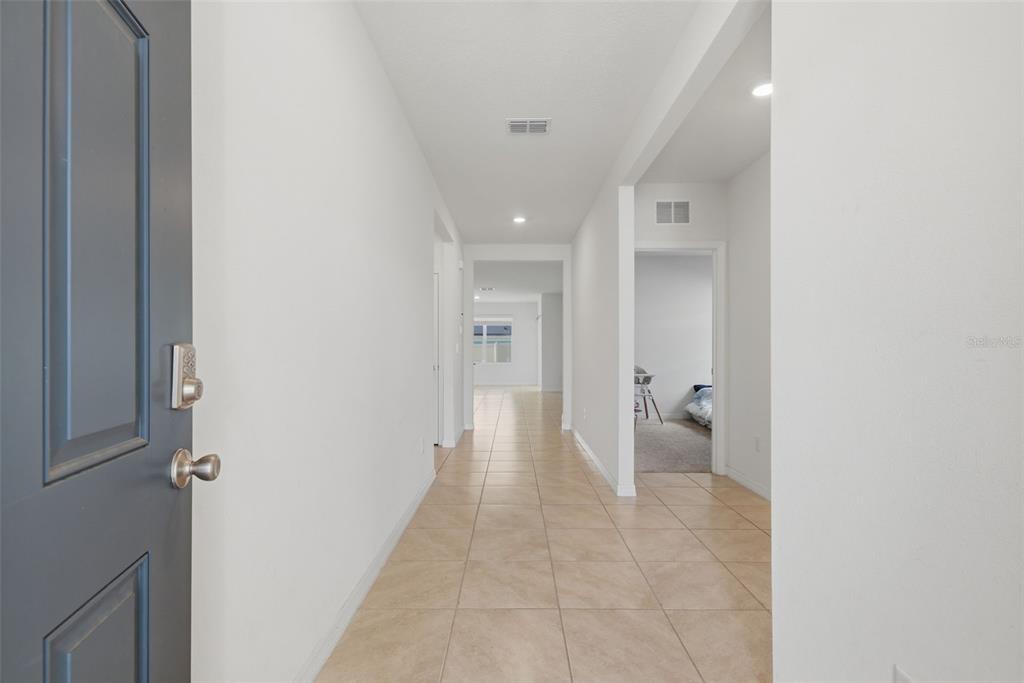 A tiled hallway leads from a dark gray front door toward an open living area — 11308 AMBER RIDGE DRIVE, ZELLWOOD, FL