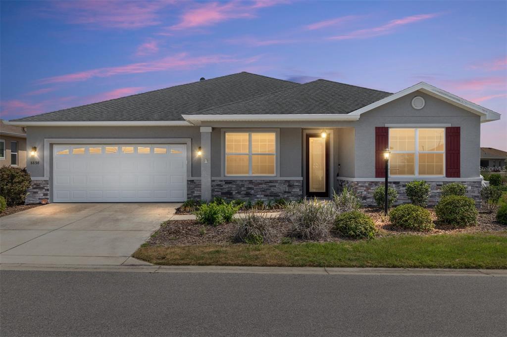 A single-story house with a gray stucco exterior, stone veneer, and a two-car garage — 8898 SW 104TH CIRCLE, OCALA, FL