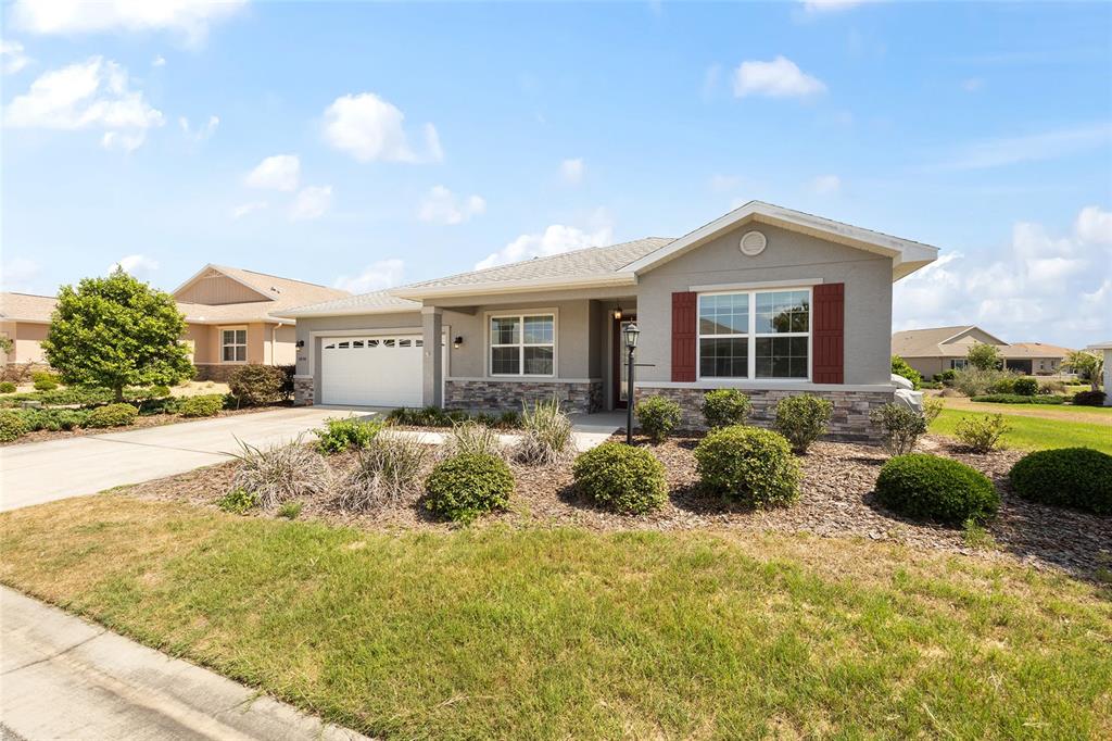 A single-story house with a gray stucco exterior, stone accents, and a two-car garage — 8898 SW 104TH CIRCLE, OCALA, FL
