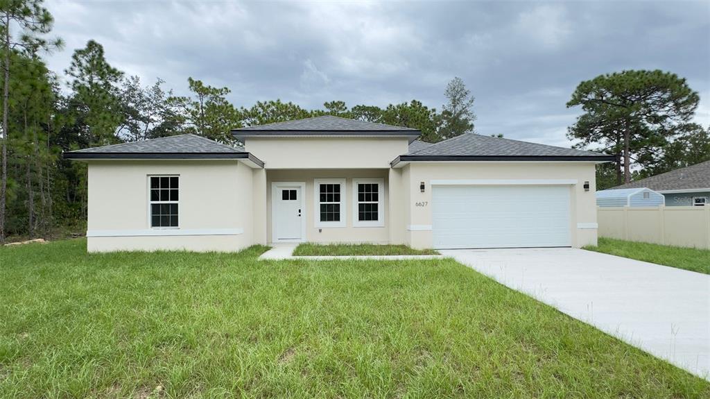 A single-story house with a white stucco exterior, a two-car garage, and a grassy yard — 6627 N HUNTINGTON TERRACE, CITRUS SPRINGS, FL