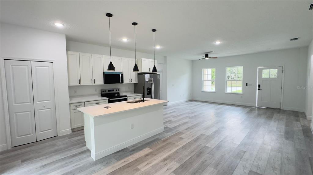A kitchen with white cabinets and a center island opens into a spacious living area — 6627 N HUNTINGTON TERRACE, CITRUS SPRINGS, FL
