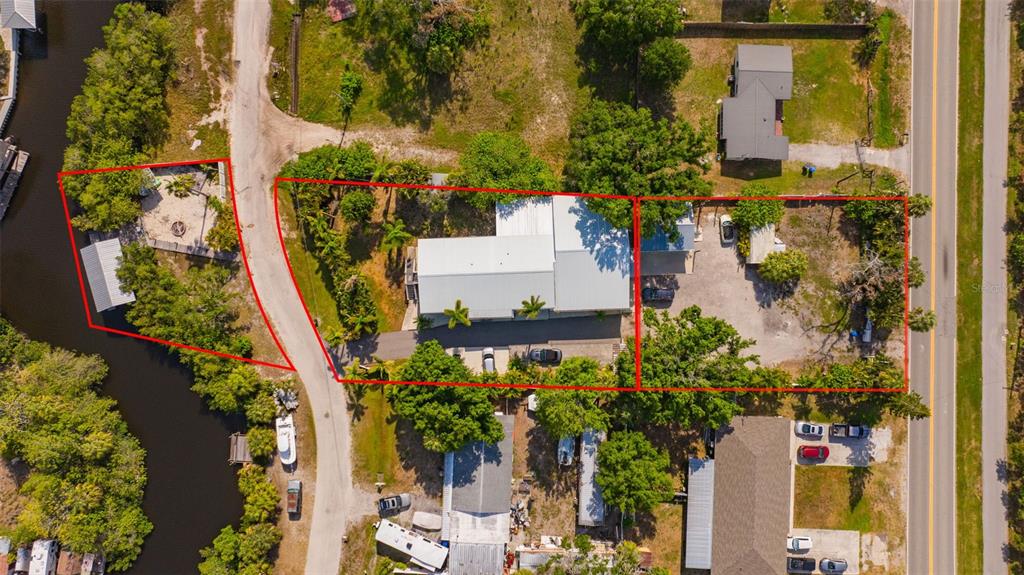 This aerial view shows three adjacent lots with a house, outbuildings, and trees near water — 815 2ND AVENUE NW, RUSKIN, FL