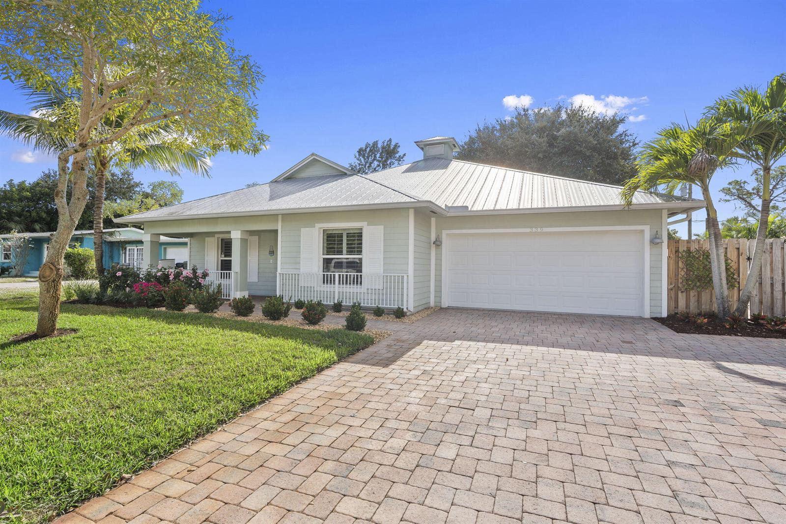 A light green house with a metal roof and a brick paver driveway — 339 SW Winnachee Drive, Stuart FL 34994, STUART, FL
