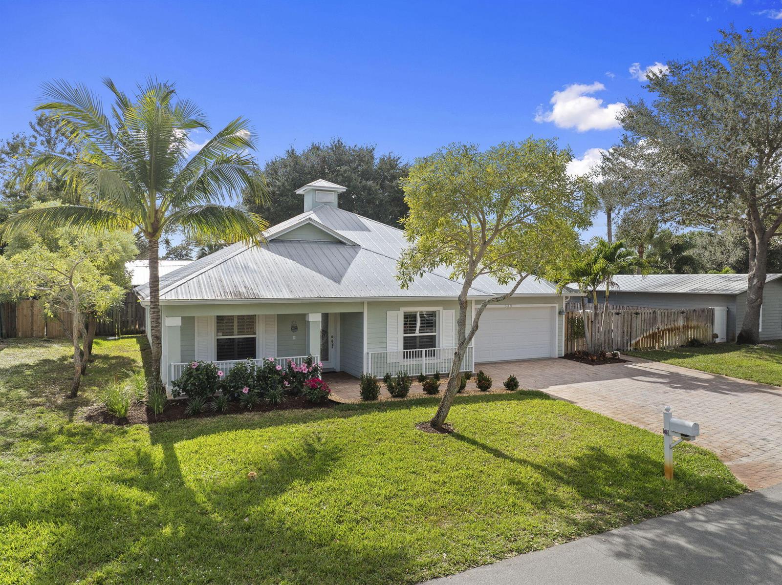 A light green single-story house features a metal roof, a cupola, and a paved driveway — 339 SW Winnachee Drive, Stuart FL 34994, STUART, FL
