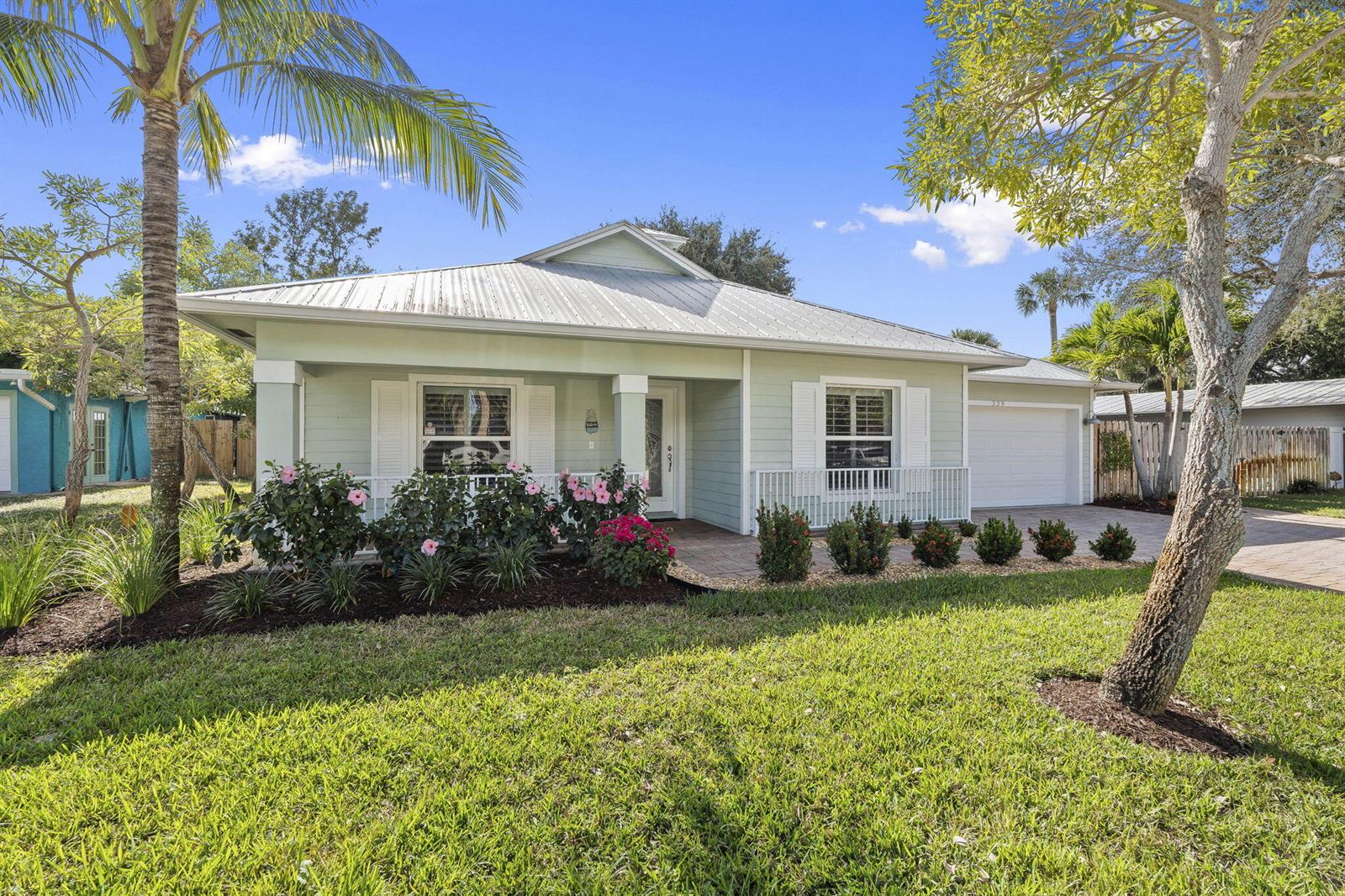 A light green single-story house with a metal roof, white shutters, and a paved driveway — 339 SW Winnachee Drive, Stuart FL 34994, STUART, FL