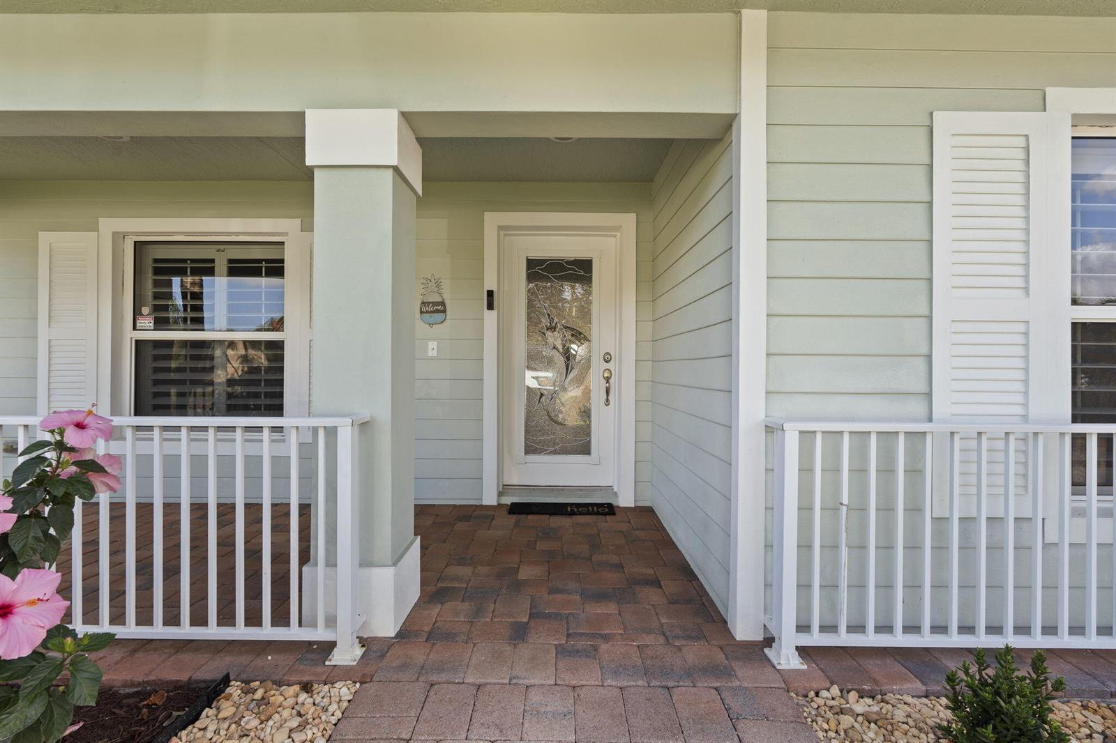 A light green house exterior features a front porch with white railings and a door — 339 SW Winnachee Drive, Stuart FL 34994, STUART, FL