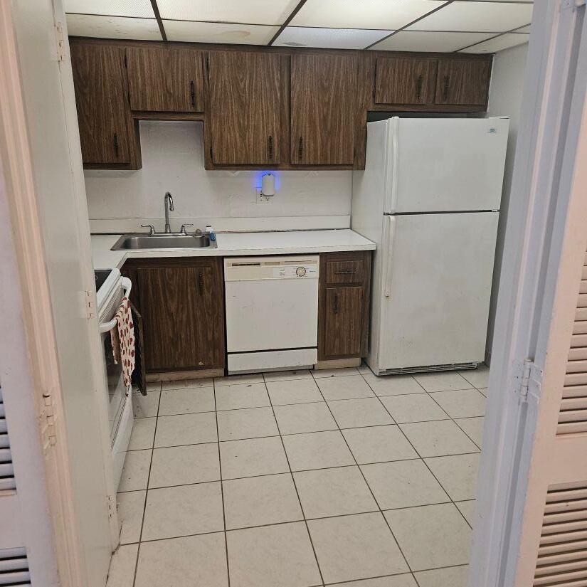 A kitchen features wood-grain cabinets, white appliances, a tiled floor, and a drop ceiling — 4174 Inverrary Drive # 603, Lauderhill FL 33319, LAUDERHILL, FL