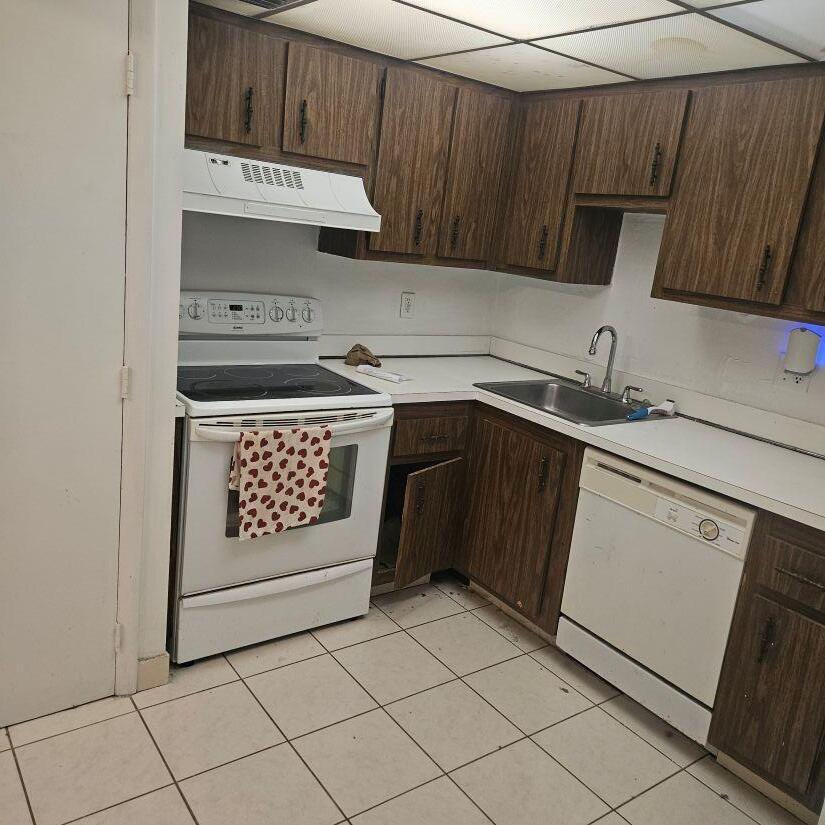 A kitchen with wood cabinets, white appliances, a tiled floor, and a drop ceiling — 4174 Inverrary Drive # 603, Lauderhill FL 33319, LAUDERHILL, FL